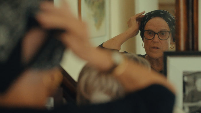 Sallie adjusting her headscarf in the mirror in Sallie’s Ashes documentary