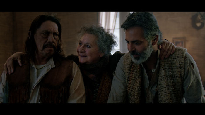 Gato and Sombra sit inside a rustic cabin in The Shadow of the Cat (2024).