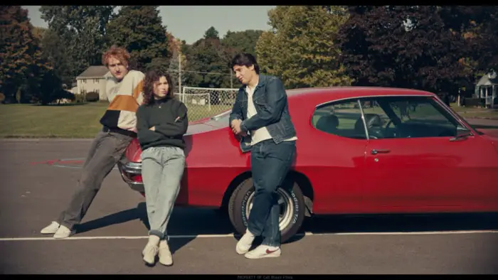 Anna Mirodin, Chase Vacnin, and Ben Heineman leaning against a red car in The Legend of Juan Jose Mundo