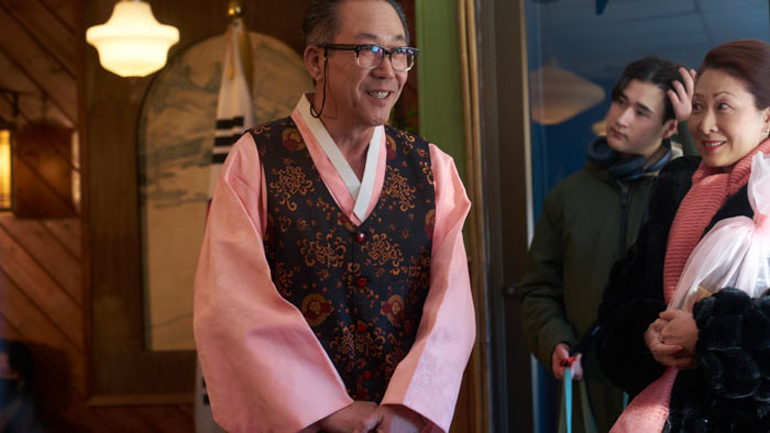 Sara (Kim Ho-Jung) smiles during a Korean community moment in The Mother and the Bear (2025).
