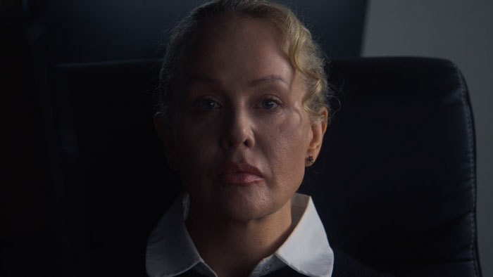 Woman seated in an office chair in a dimly lit workplace scene from Time to Go