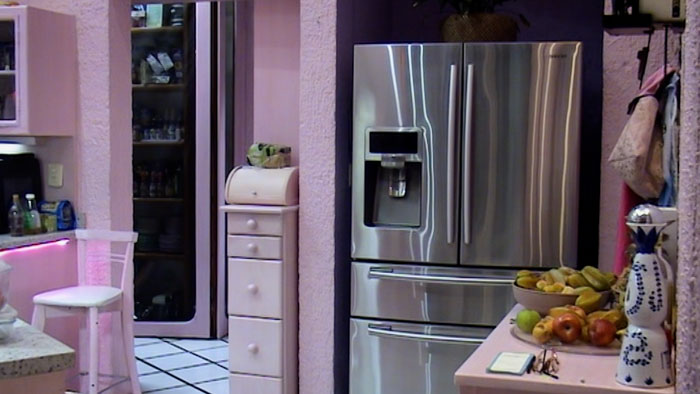 Retro pink kitchen scene from Diana & Minerva featuring a stainless steel refrigerator and fruit display
