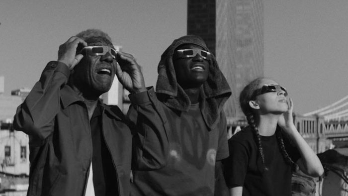 Sully and companions watch the sky wearing eclipse glasses in The Projectionist (2026)