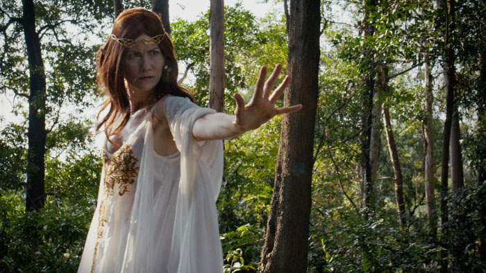 High Elf woman in white gown raises her hand in the forest in The Warriors Tale: Circle of Hatred (2026).