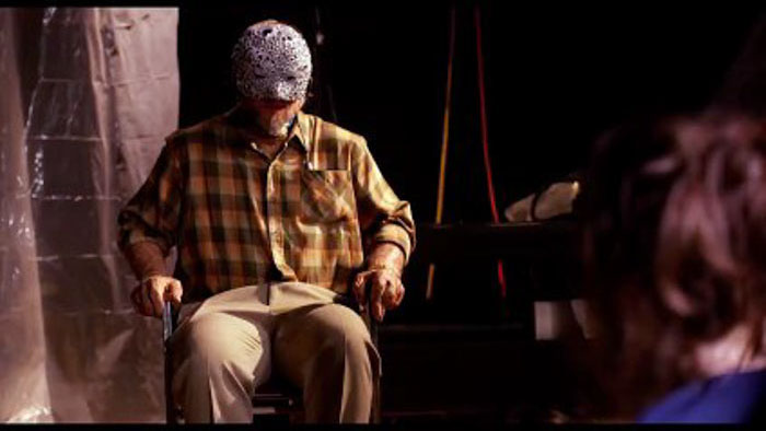 Masked kidnapper wearing a googly-eye mask sitting in a chair in Velvicide (2026)