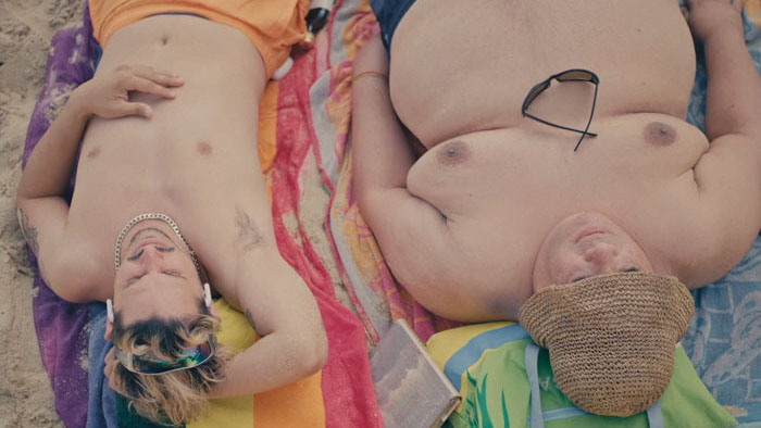 Cherri (Juan Miguel Más) and Tim (Noslen Sánchez) lie side by side on the beach in Cherri.