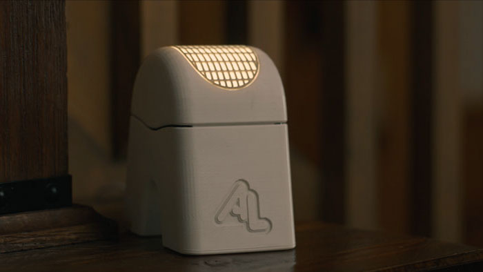 The AL artificial intelligence assistant device sitting on a wooden table in the remote cabin in the thriller Remote (2026).