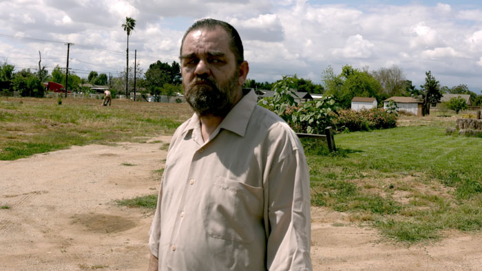 An unidentified man stands in an open lot in The Abused.