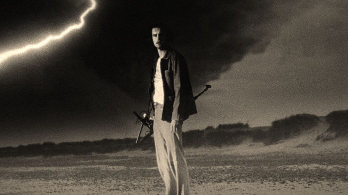 Jim Baitte (Jack Redmayne) stands on a stormy beach beneath lightning in The Peril at Pincer Point.