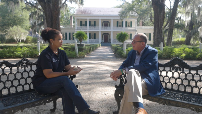Lauren Cudmore conducting an interview on the grounds of a Southern plantation in Vacation Plantation.