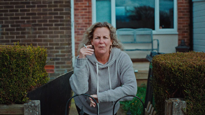 Janet (Lorraine Stanley) smoking outside her home in Departures.