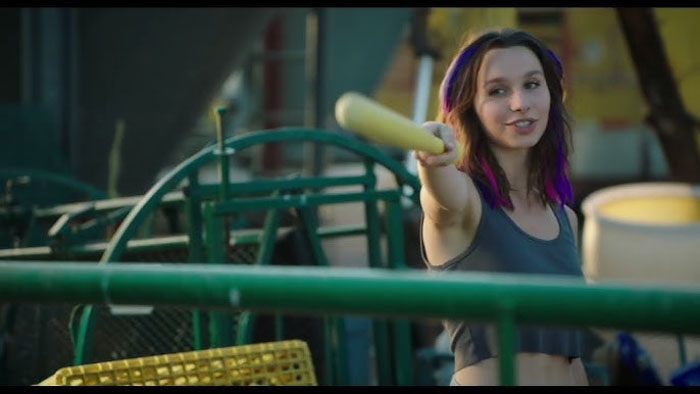 Olive (Jordan Cathryn) playfully holding a yellow baseball bat in Finding the Zone.