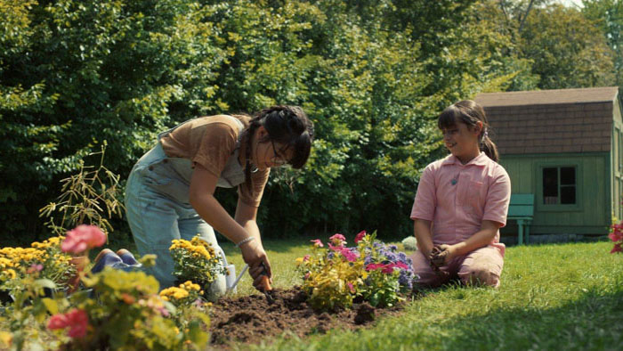 Callie (Lexi Perkel) plants flowers in the garden in Mabel. 