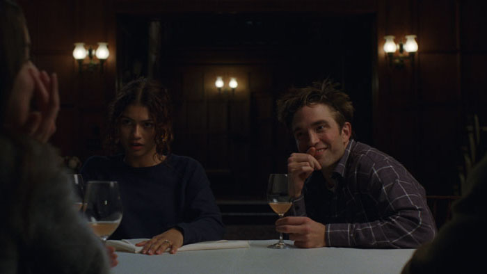 Charlie (Robert Pattinson) and Emma (Zendaya) sit at a dinner table in The Drama.