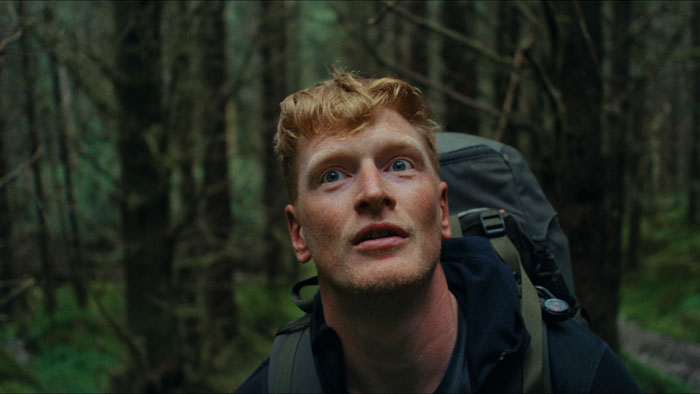 Chris (Bart Harder) hiking through the forest in The North. 