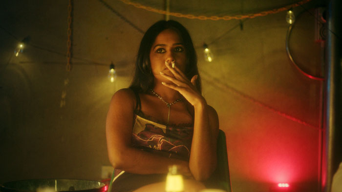 Gen (Avalon Fast) smoking in a dimly lit room in The Serpent’s Skin.