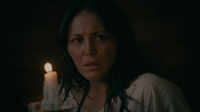 Jo Beckett (Cassandra Scerbo) holds a candle in The Wolf And The Lamb.