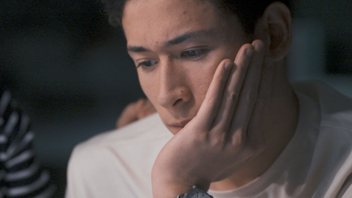 Lucas Browde in Unbroken: The Untold Story of Shen Yun during a reflective close-up moment.