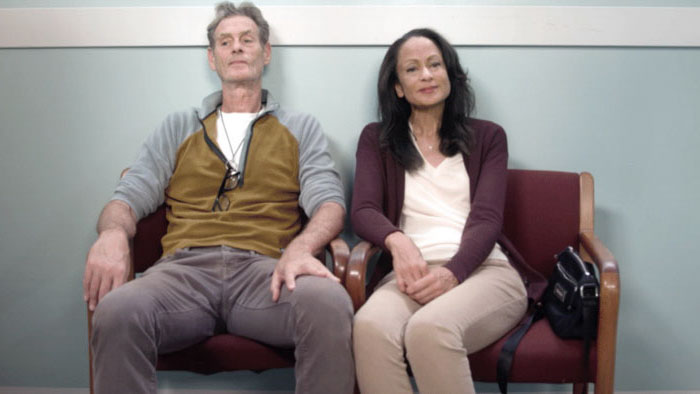 Anne-Marie Johnson as Joe sits in a waiting room beside a male companion in The Addiction of Hope.