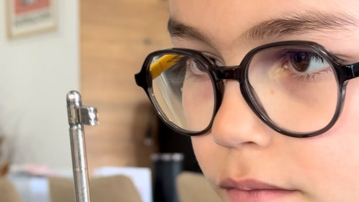 Nino Valenti as The Son peers through large glasses in a close-up scene from Behind the Door.