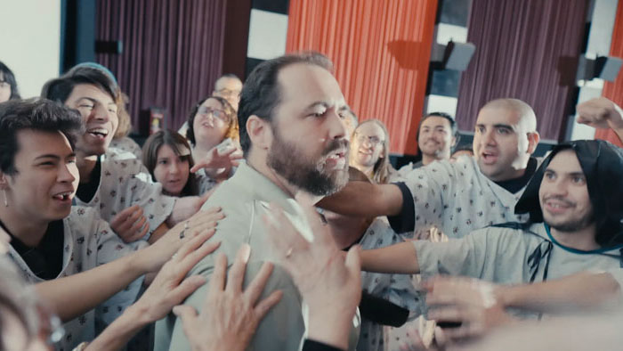 Phil surrounded by cult members in a worship scene in Church of Phil.