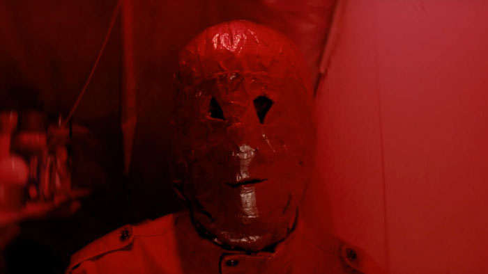 The masked Tapeface killer appears under red light in Method.