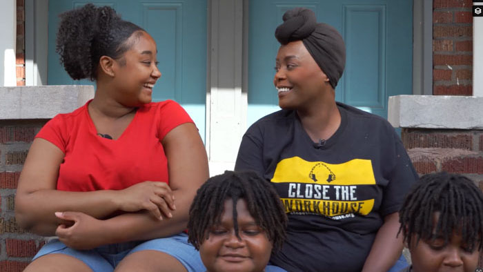 Inez Bordeaux smiles with family members on the front porch in The End of Isolation.