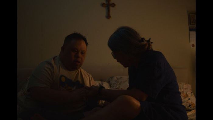 Two people in an intimate conversation in a warmly-lit bedroom scene from The Sharp Point of Time. 