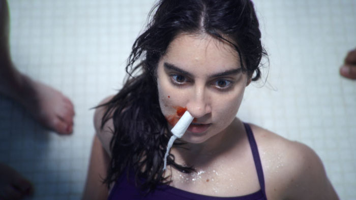 Tori (Nanouli Shevardnadze) looks up from the pool with a nose tampon in Big Nose.