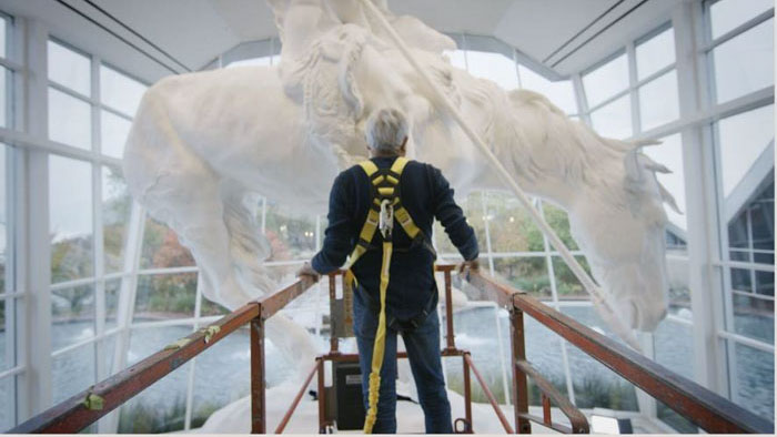Michael Naranjo stands before a large horse sculpture in Dream Touch Believe.