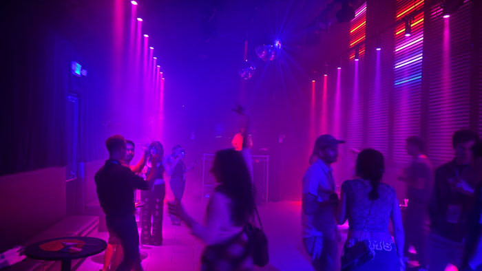 Filmmakers and guests dance under purple and pink neon lights at the 2026 Palm Springs International ShortFest after party.