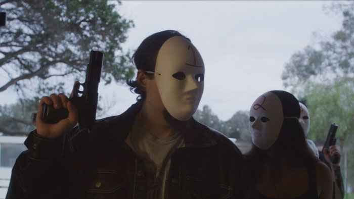 Two masked, armed gang members stand menacingly outdoors in Pancake Man.