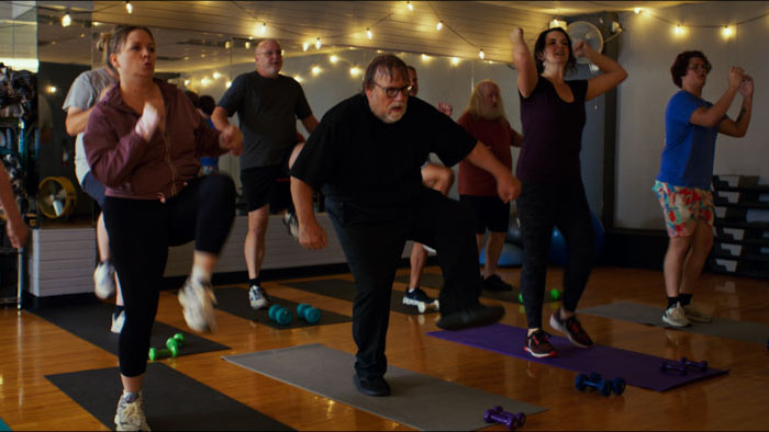 Father Joseph (Kevin P. Farley) leads an aerobics class at Solomon's Porch in Pickleball (2026).
