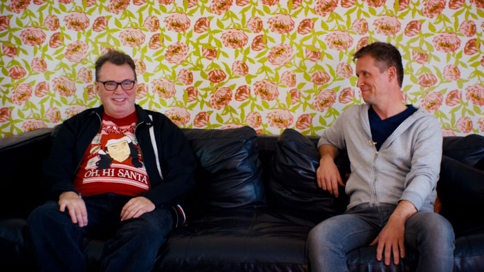Zsolt Magyar and Tim D. Lloyd sit on a black couch for their interview in Room Tone: The Sound of "The Room."