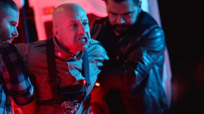 Subject 13 (Sawl Gud) snarls while restrained in a neon-lit scene from S86.