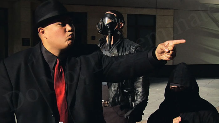 Smiley points while Burning Man in a gas mask and a robed ninja stand behind him in Smoked Too.