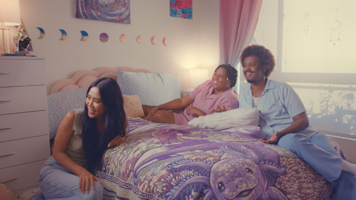 Becca (Marylynn Sienna), Sasha (Jasmine Vaughan), and Gray (Moe Dagane) relax in a bedroom in The Closet.