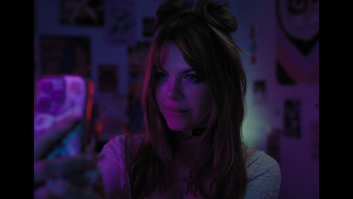 Sophia Wright-Mendelsohn bathed in purple neon light in The Second Screen.