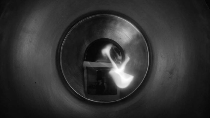 A burning photograph inside a metallic circular chamber in To Beyond.