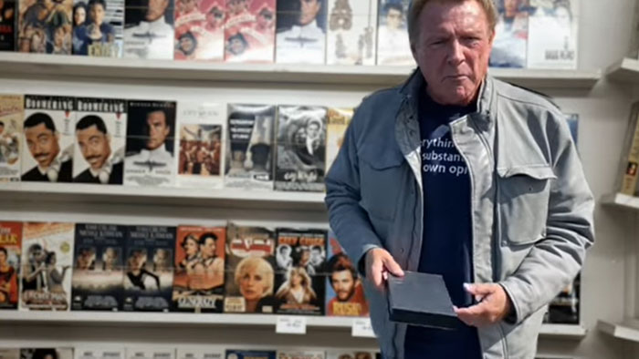 Ron Preston as a customer holds a DVD case inside a video store in Video Clerk.