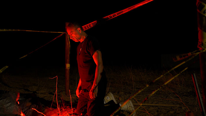 Michaels (Michael Peter Bolus) stands alone at night near caution tape and smoldering embers in A Sense of Dread.