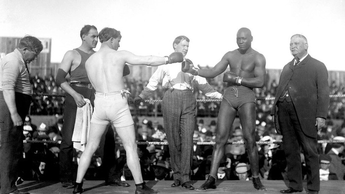 Jack Johnson touching gloves with a white boxer before a historic boxing match in Black Men in Uniform: The Untold Story.