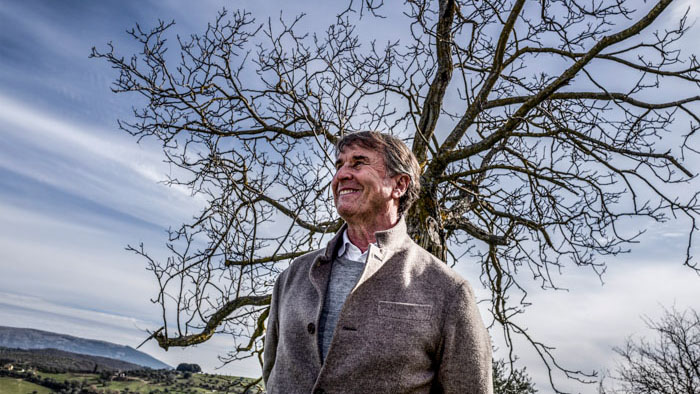 Brunello Cucinelli smiles beneath a bare tree in the Umbrian countryside in Brunello: The Gracious Visionary.