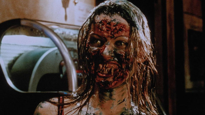 A blood-covered undead woman reveals monstrous teeth in Legion of the Dead.