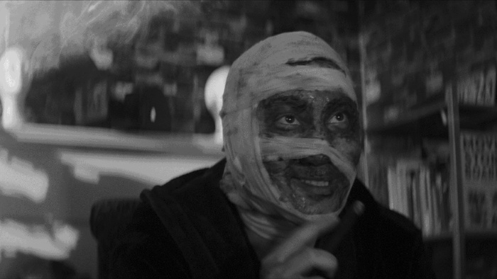 An actor wrapped in facial bandages plays the thief during the store robbery scene in Meta Take One.