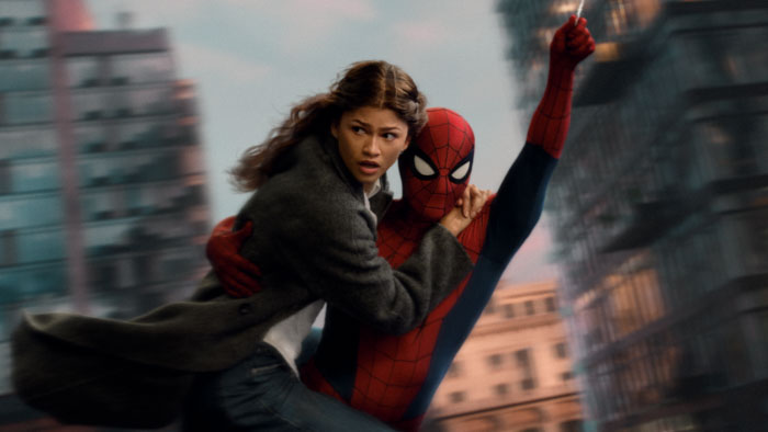 MJ (Zendaya) clings to Spider-Man (Tom Holland) as he swings above the city in Spider-Man: Brand New Day.