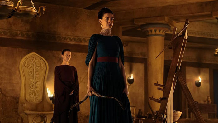 Penelope (Anne Hathaway) holds a bow in the palace of Ithaca in The Odyssey.