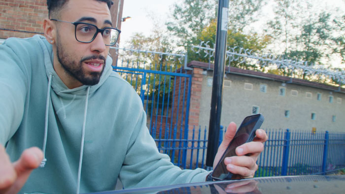 Jordan Faiyaz (Rico Bowlin) holds his phone while leaning on a car in The Worth of Life.