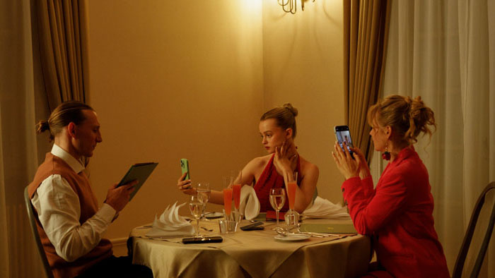 Luca (Maja Bons) sits with her family, Chris and Stella, glued to phones in Babystar.