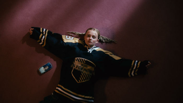 Luca (Maja Bons) lies spread-eagle on the floor in a hockey jersey in Babystar.